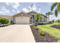 Inviting single-story home with a two-car garage, manicured lawn, and a decorative palm tree at 6001 Condor Dr, Lakeland, FL 33809