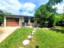 Charming single-story home featuring a well-manicured lawn, stone walkway and attached garage at 722 N Nashua Ave, Fort Meade, FL 33841