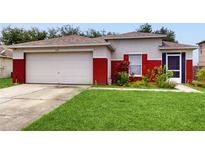 Charming single-story home featuring a two-car garage and vibrant red accents on the exterior and freshly mowed lawn at 7337 Hunters Greene Cir, Lakeland, FL 33810
