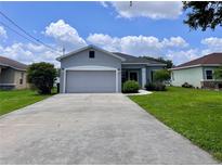 Charming single-story home with a two-car garage, lush landscaping, and a well-maintained front yard at 14 Morton Rd, Winter Haven, FL 33881