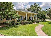 Charming single-story home with a manicured lawn, brick walkway, and stately white columns at 1589 Royal Forest Ct, Lakeland, FL 33811
