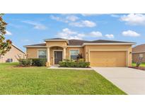 Charming single-story home with a well-manicured lawn and a two-car garage on a sunny day at 1975 Country Manor St, Bartow, FL 33830