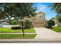 Charming two-story home showcasing a well-manicured lawn, tasteful landscaping, and a welcoming two-car garage at 228 Magneta Loop, Auburndale, FL 33823