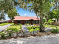 Charming log home with a red metal roof, mature trees, and landscaped yard at 330 Diesel Rd, Mulberry, FL 33860