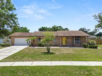 Charming single-story brick home with a well-manicured lawn, bright yellow door, and attached two-car garage at 3315 Cross Fox Dr, Mulberry, FL 33860