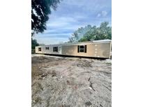 Tan mobile home showing the exterior with dark shutters and an unkempt yard at 711 Whispering Pines Dr, Auburndale, FL 33823