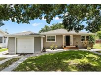 Charming single-story home with neutral siding, green lawn and complemented by mature trees overhead at 819 Glendale St, Lakeland, FL 33803