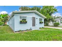 Charming blue home with a well-manicured lawn and flower boxes under the windows at 980 S Mill Ave, Bartow, FL 33830
