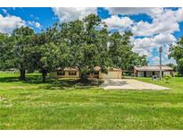Charming brick home with an attached garage, large trees, and expansive grassy front yard at 10 Webb Rd, Winter Haven, FL 33881