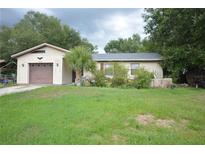 Single story home with attached garage, small palm tree and green lawn at 240 Lake Thomas Dr, Winter Haven, FL 33880