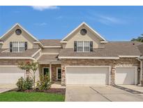 Charming townhouse featuring stone accents, attached garages and well maintained landscaping under a bright blue sky at 4309 Shipp Ct, Lakeland, FL 33813