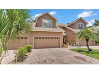 Charming townhome featuring a brick driveway, a two-car garage, and lush tropical landscaping at 6365 Torrington Cir, Lakeland, FL 33811