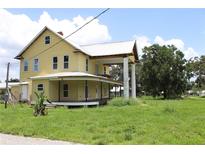 Charming two-story yellow home featuring a wraparound porch and a metal roof at 701 1St Ne St, Fort Meade, FL 33841