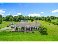 Aerial view captures a serene estate with a large house, a pond, green fields, and mature trees at 15195 Angus Rd, Polk City, FL 33868