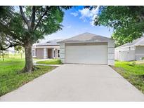 Charming single-story home with a two-car garage and solar panels on a sunny day at 169 Birmingham Dr, Kissimmee, FL 34758