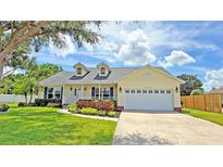 Charming single-story home with dormer windows, landscaped yard, and a two car garage on a sunny day at 2264 Palmview E Cir, Auburndale, FL 33823