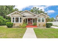 Charming bungalow with red front porch, walkway and well-manicured lawn under a partly cloudy blue sky at 236 E Seminole Ave, Lake Wales, FL 33853