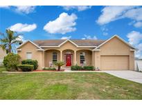 Charming single Gathering home with a well-manicured lawn and inviting front porch with a red door at 5370 Knights Station Rd, Lakeland, FL 33810