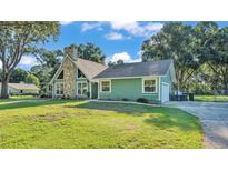 Charming single-story home with stone chimney, green siding, and mature trees at 6533 Angus Dr, Lakeland, FL 33810