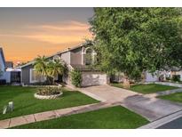 Charming two-story home featuring a well-manicured lawn, mature tree, and a gray stucco exterior at 8818 Tottenham Way, Kissimmee, FL 34747