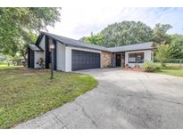 Charming home featuring stone accents, dark grey garage door, and a well-maintained front yard at 910 Van Dr, Auburndale, FL 33823