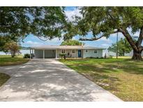 Charming home exterior featuring a covered carport, a vibrant blue front door and a lake view at 21 Lake Ave, Winter Haven, FL 33880