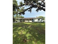 Charming single-story home featuring a lush lawn, mature trees, and a convenient carport at 21 Lake Ave, Winter Haven, FL 33880