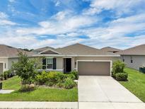 Charming single-story home featuring a well-manicured lawn, front garden and a two-car garage at 221 Hilltop Bloom Loop, Haines City, FL 33844