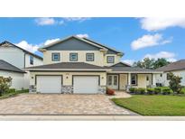 Charming two-story home featuring a three-car garage, a brick-paved driveway, and well-maintained landscaping at 2736 Sunrise Landing Ln, Lakeland, FL 33812