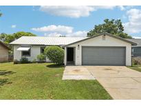 Charming single-story home featuring a well-maintained lawn, a metal roof and an attached garage at 3854 Feather Dr, Lakeland, FL 33812