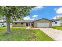 Inviting single-story home featuring a well-manicured lawn, mature tree, and attached two-car garage at 4622 Grovecrest Dr, Lakeland, FL 33813