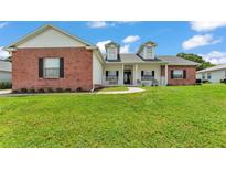 Charming home featuring a front porch, brick accents, dormer windows, and a well-maintained green lawn at 5579 Summerland Hills Dr, Lakeland, FL 33812