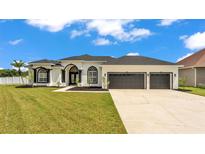 Beautiful home with a well-manicured lawn, three-car garage, and stylish black and white exterior at 6707 Hillis Dr, Lakeland, FL 33813