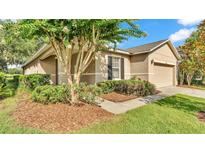 Charming home exterior featuring a well-manicured lawn and lush landscaping, with a tan exterior at 6964 Lake Eaglebrooke Dr, Lakeland, FL 33813