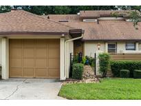Charming townhome featuring a one-car garage, brick pathway, and manicured landscaping at 925 Fenton Ln # 18, Lakeland, FL 33809