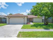 Charming single-story home with a well-manicured lawn, mature tree, and an attached two-car garage at 1081 Sunshine Sw Way, Winter Haven, FL 33880