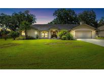 Charming single-story home with lush lawn, mature trees and inviting front entrance and attached two car garage at 2208 Deerbrook Dr, Lakeland, FL 33811