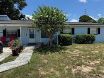 Charming single story home with a tree, lush bushes, and cheerful front door at 225 W Orange St, Lake Alfred, FL 33850