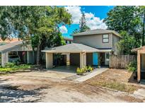 Charming home featuring a covered parking area, complemented by verdant landscaping and a welcoming blue door at 3542 Raintree Ct, Lakeland, FL 33803