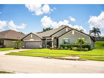 Charming single-Gathering home showcasing a well-manicured lawn and gray exterior paint at 4222 Juliana Lake Dr, Auburndale, FL 33823