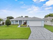 Charming single-story home with a manicured lawn, light blue exterior, and stone-patterned driveway at 5771 Macaw Pl, Lakeland, FL 33809