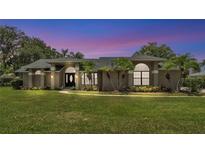 Beautiful home with lush landscaping, mature palms, and manicured lawn at dusk at 5819 Hollyhock Dr, Lakeland, FL 33813