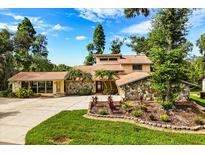 Charming home featuring a stone facade, mature landscaping, and a well-manicured lawn at 6033 Mountain Lake Dr, Lakeland, FL 33813