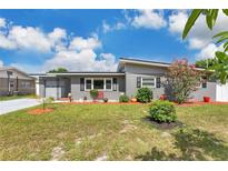 Charming gray single-story home featuring a manicured front yard with a beautiful blossoming tree at 686 22Nd Nw St, Winter Haven, FL 33880