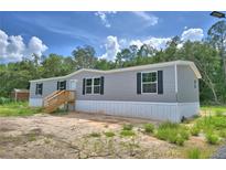 Charming single-story home features gray siding, black shutters, and a welcoming wood staircase at 12440 Ranchland Trl, Lakeland, FL 33809