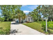 Charming home featuring a long driveway, lush lawn, and beautiful trees for curb appeal at 423 Avenue H Se, Winter Haven, FL 33880