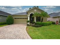 Charming single-story home featuring a well-manicured lawn, brick driveway, and an attached two-car garage at 6408 Christina Chase Pl, Lakeland, FL 33813