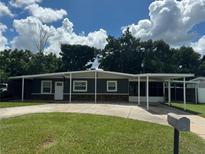 Charming one-story home featuring a well-manicured lawn, covered parking, and classic architectural details at 508 Garden N Dr, Lakeland, FL 33813