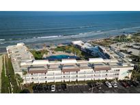 Breathtaking aerial view of the condo complex with its pool, lush landscaping, and direct beach access at 3663 S Atlantic Ave # 21C, New Smyrna Beach, FL 32169