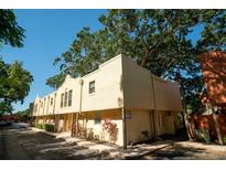 Exterior of a two-story apartment building featuring tan stucco walls, a paved sidewalk, and mature tree coverage at 788 E Michigan St # 18, Orlando, FL 32806